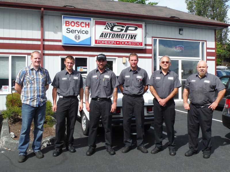 The crew out front of the shop, a white classic Mercedes parked behind
