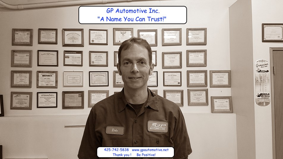 Eric Debolt in his name-patch work shirt, standing in front of the wall of framed training certificates behind our counter