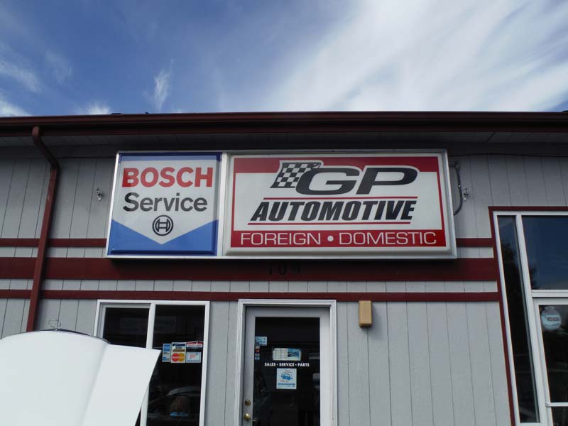 Our GP Automotive lightbox sign and the Bosch Service lightbox beside it, on the gray siding above our door