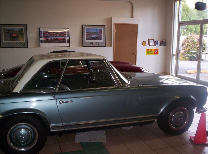 An ice-blue Mercedes Pagoda parked inside our lobby, framed racing prints on the wall behind it